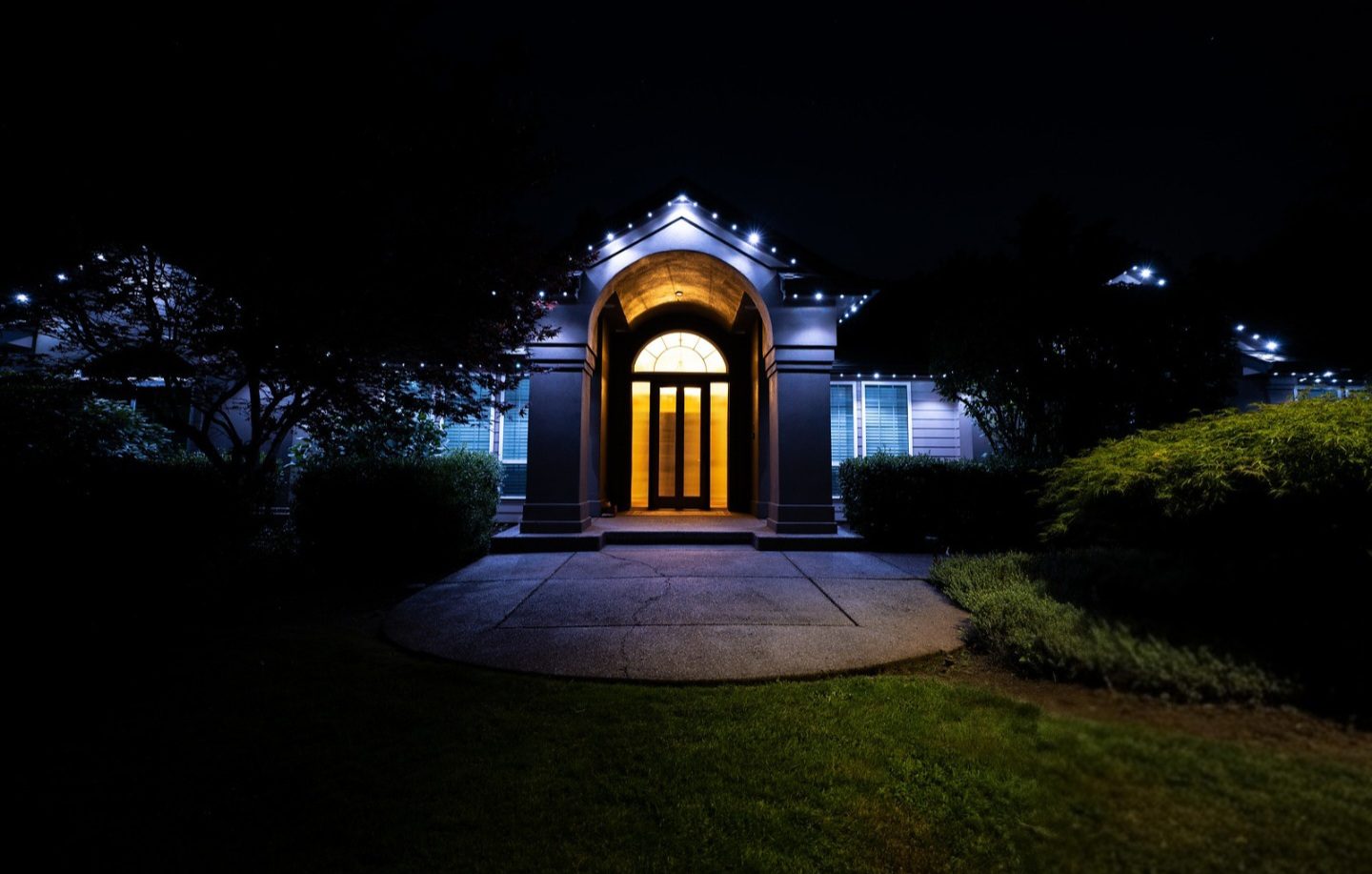 Salem home with arched entryway lit in cool white permanent LED lights at night