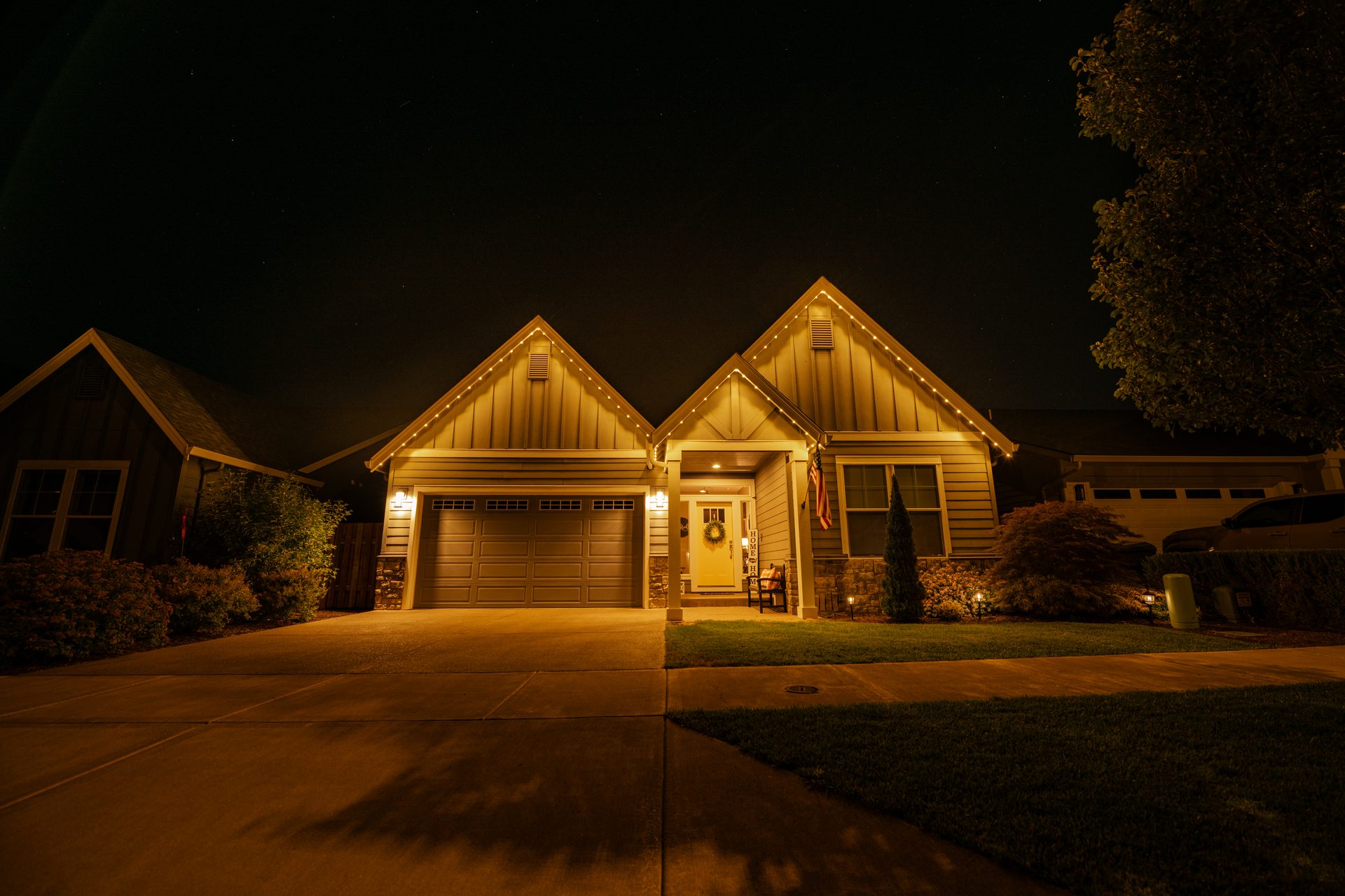 Two-peak Salem home with warm white permanent LED roofline lighting at night