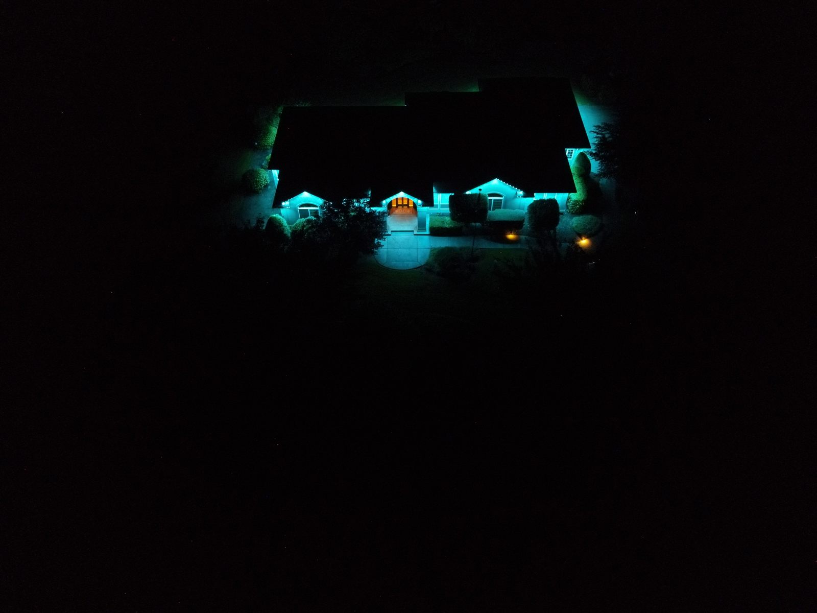 Aerial drone shot of the McCanna home with teal LED roofline lighting at night
