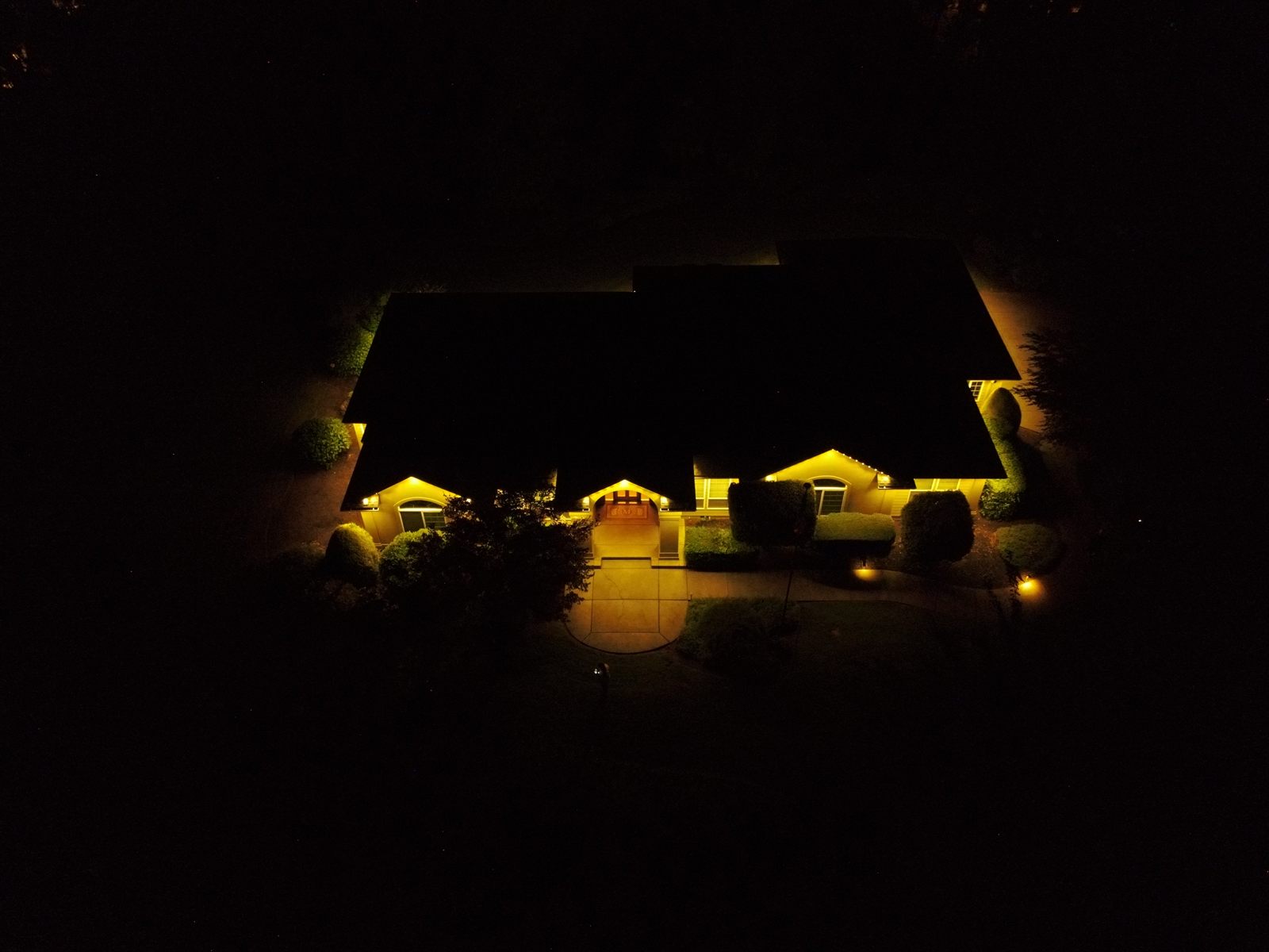 Aerial drone shot of the McCanna home with warm white LED roofline lighting at night