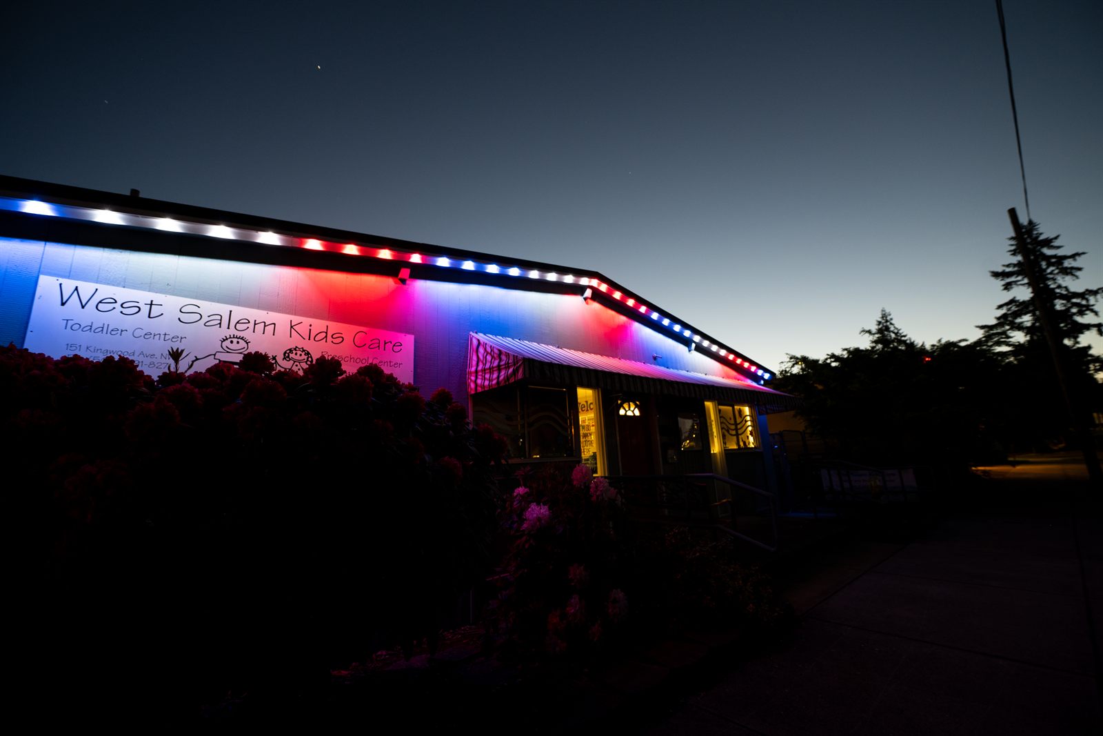 West Salem Kids Care childcare business with permanent LED roofline lighting in red, white, and blue installed by Timber Glow Lights